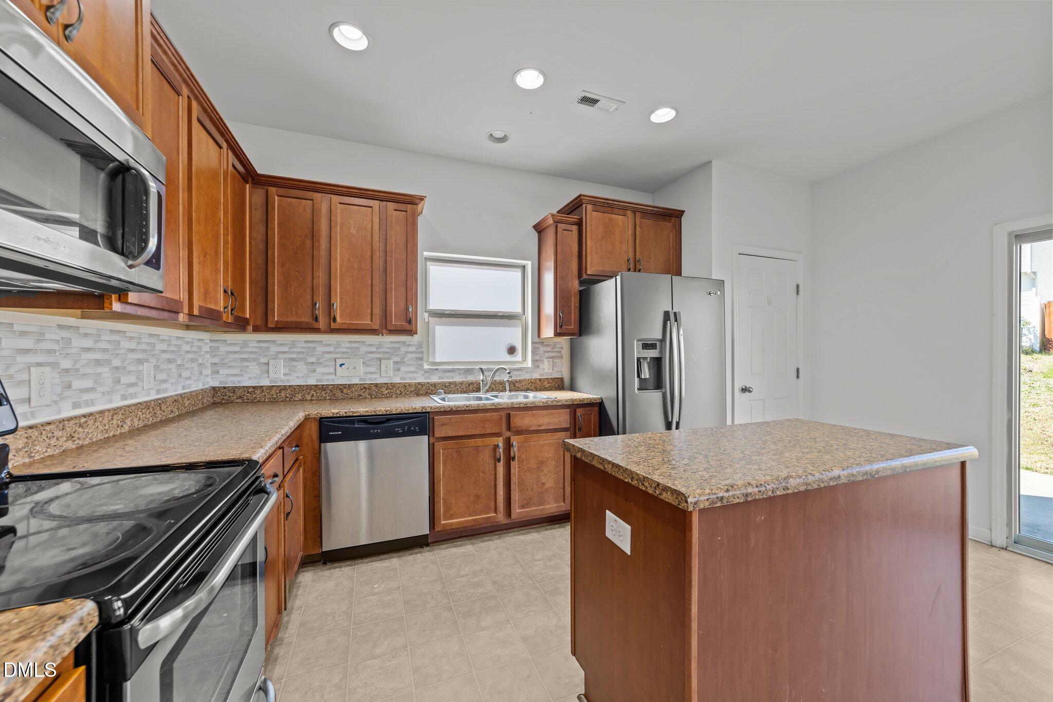1445 Lombar Street Raleigh, NC 27610 - Photo 9 of 20 a kitchen with stainless steel appliances granite countertop a sink stove microwave and refrigerator