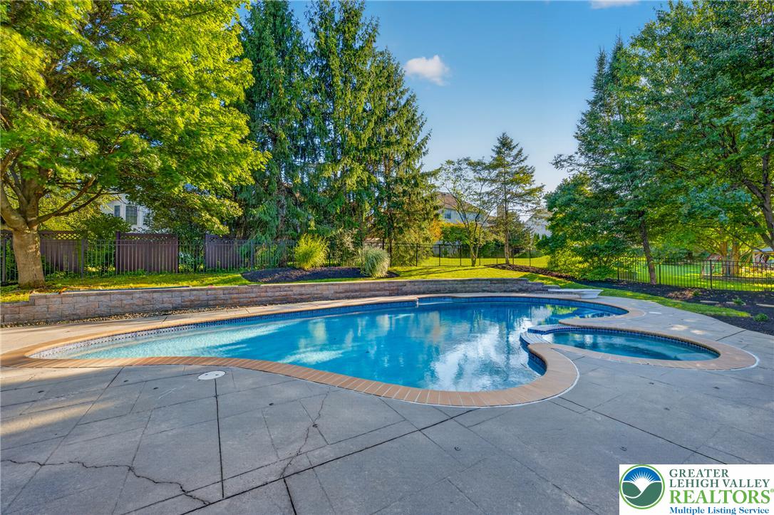 3130 Muirfield Road Center Valley, PA 18034 - Photo 63 of 63 Mature trees frame a spacious concrete patio surrounding a custom-shaped swimming pool and spa.