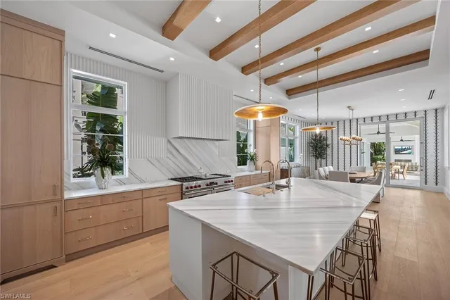 a dining hall with stainless steel appliances kitchen island granite countertop a table chairs and a sink