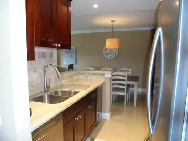 a kitchen with stainless steel appliances granite countertop a sink a stove and a refrigerator with wooden floor