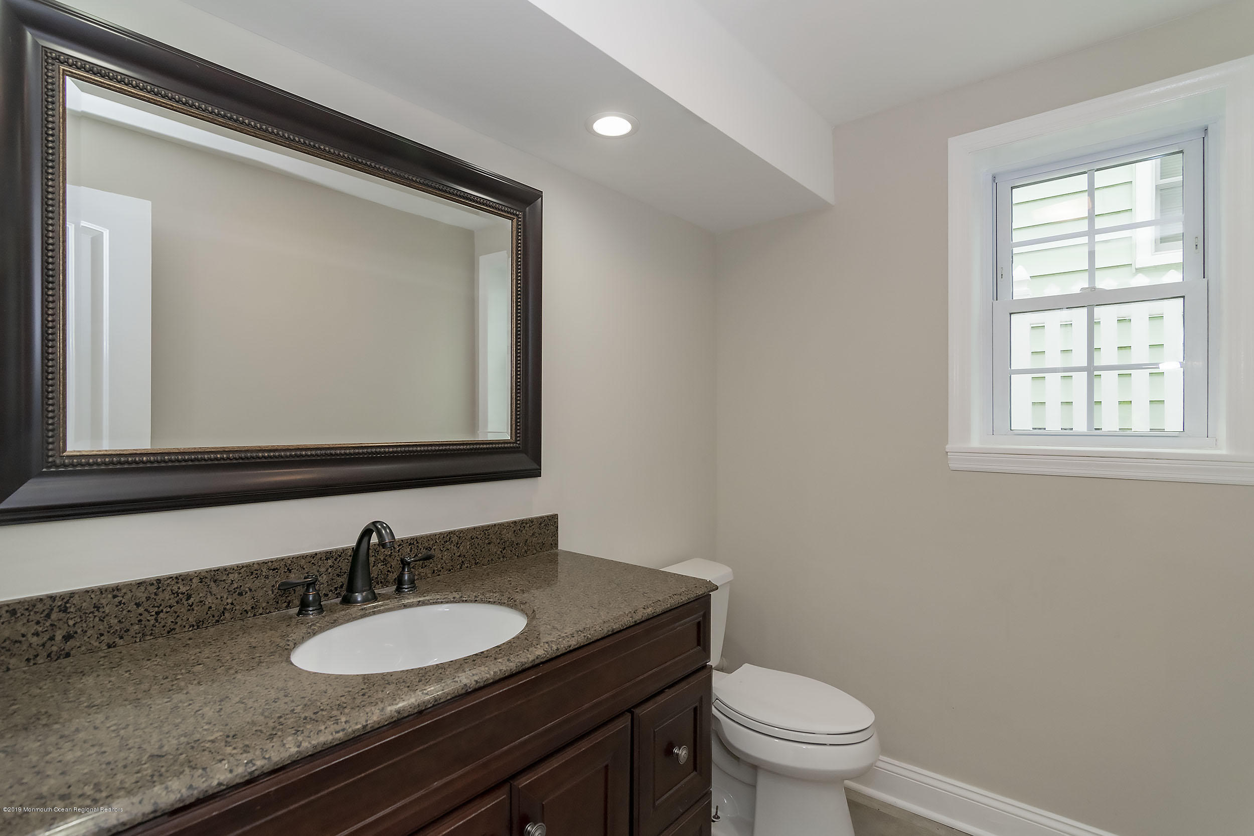 1521 Treeneedle Road Point Pleasant, NJ 08742 - Photo 17 of 33 a bathroom with a granite countertop toilet a sink and a mirror