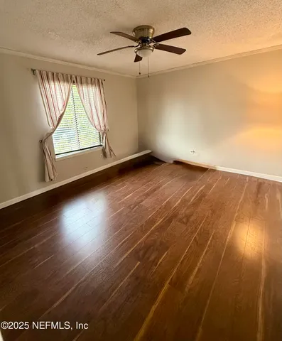 an empty room with wooden floor fan and windows