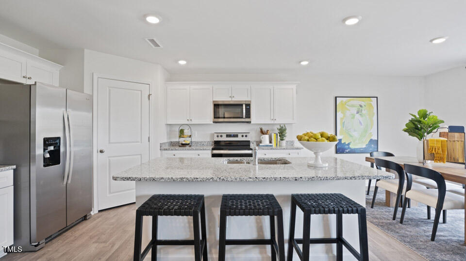 5917 Sodium Street Raleigh, NC 27610 - Photo 12 of 24 a kitchen with granite countertop a refrigerator a stove a microwave oven a dining table and chairs