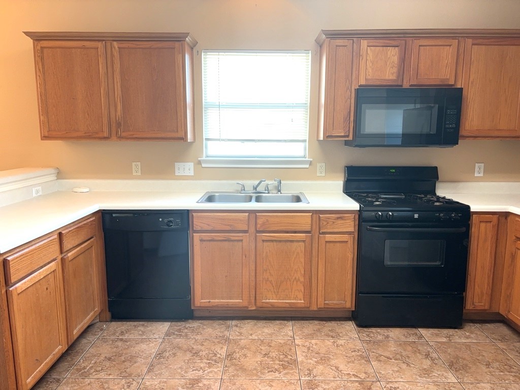 2869 Southampton Way, Unit B Round Rock, TX 78664 - Photo 7 of 19 Kitchen with window over sink, wood cabinetry, tile flooring and black appliances.