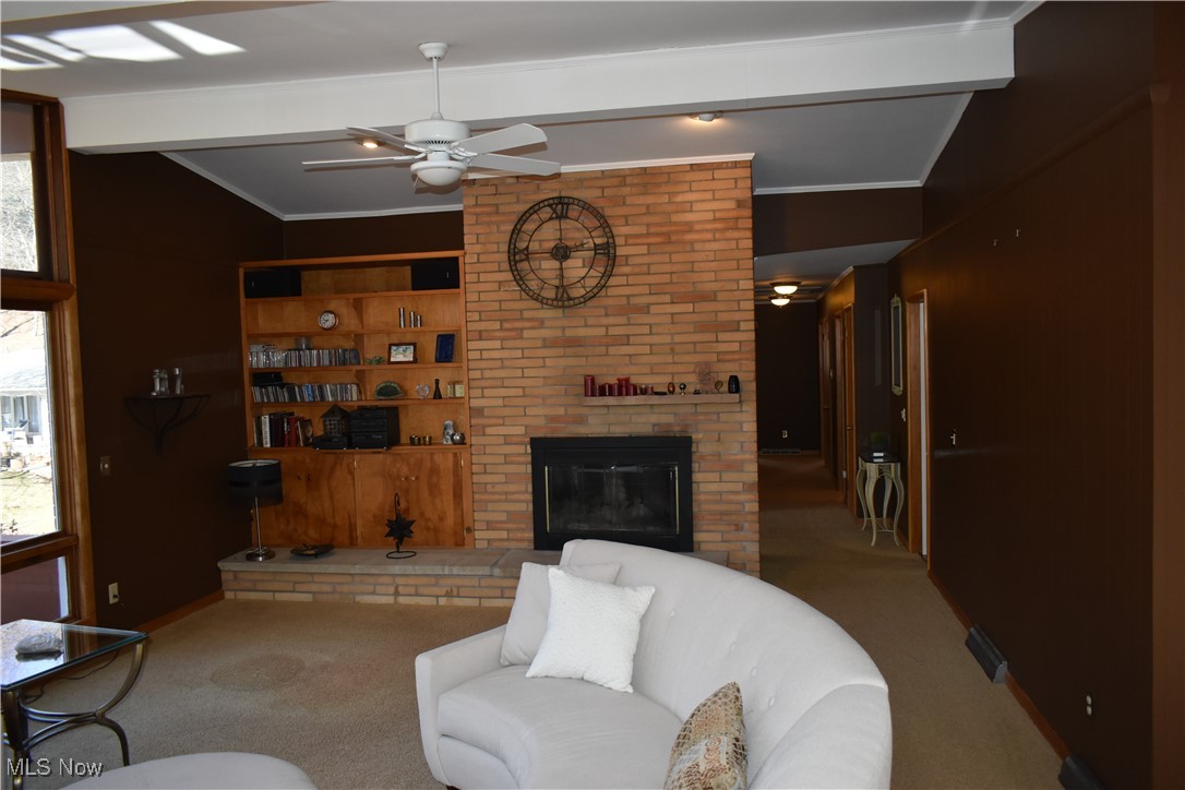 735 Sheridan Road Coshocton, OH 43812 - Photo 14 of 34 Living room with lofted ceiling with beams, ornamental molding, carpet flooring, ceiling fan, and a fireplace