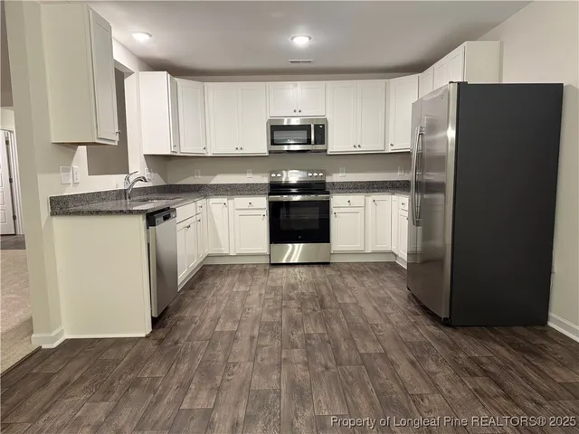 a kitchen with granite countertop a refrigerator and a stove top oven