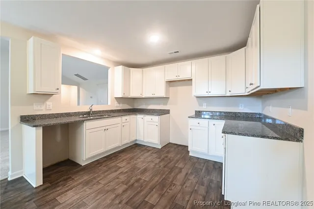 a kitchen with granite countertop white cabinets and white appliances
