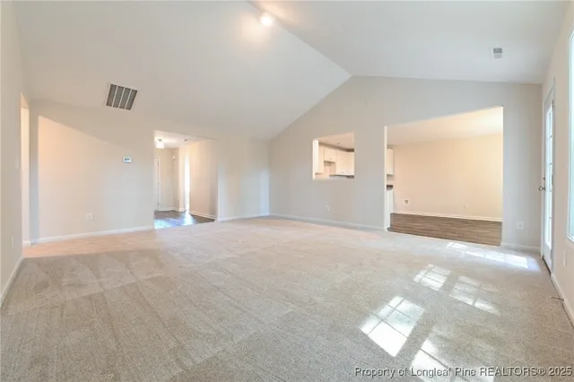 a view of an empty room with window and wooden floor