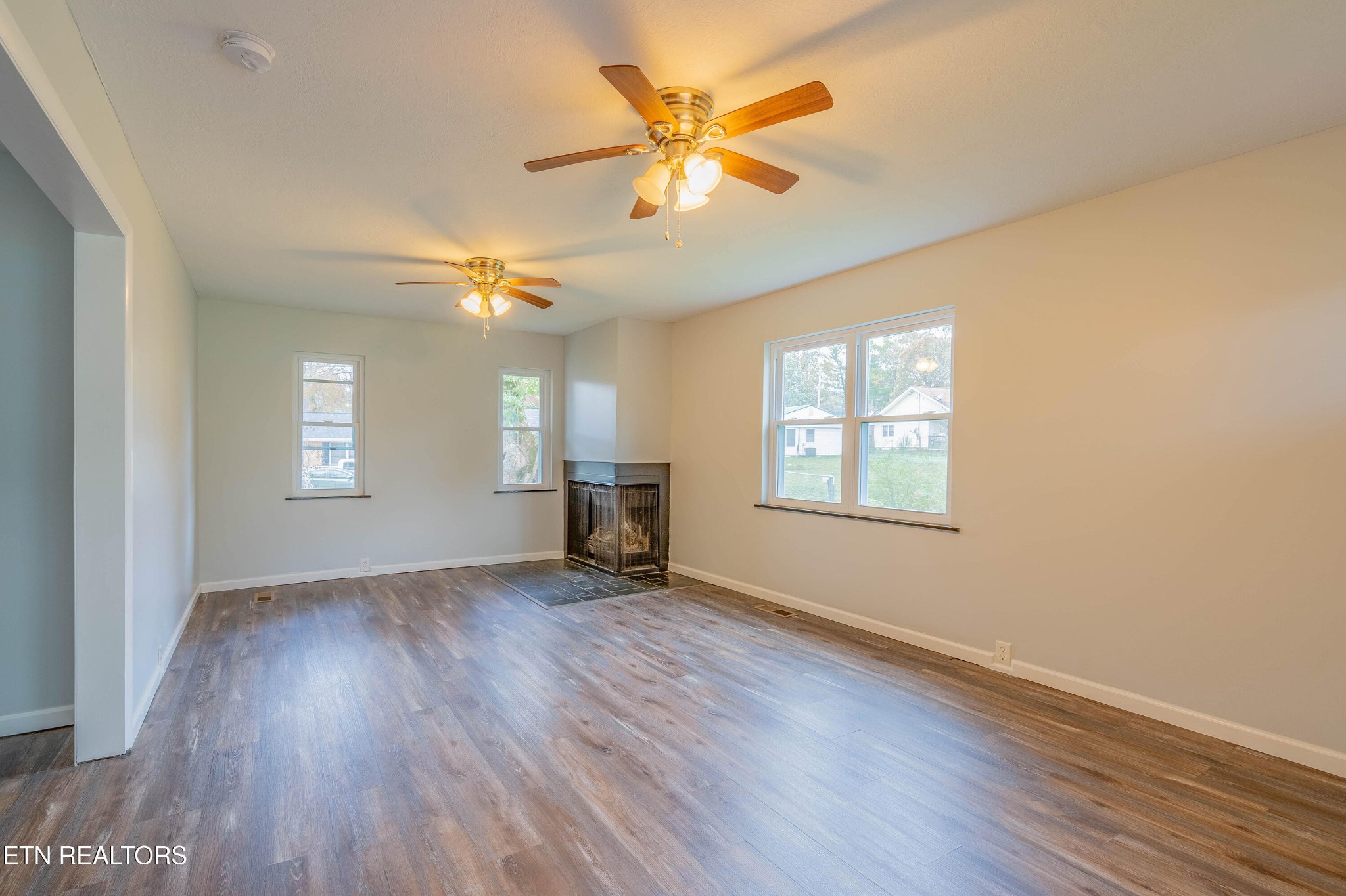 115 Manchester Road Oak Ridge, TN 37830 - Photo 7 of 22 an empty room with wooden floor chandelier fan and windows