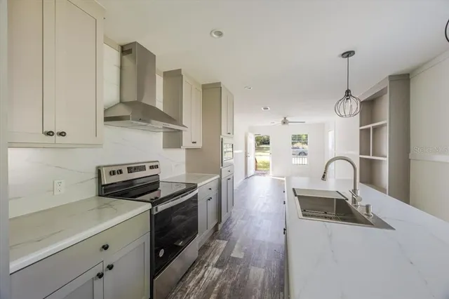 a kitchen with granite countertop a stove a sink a refrigerator and wooden floor