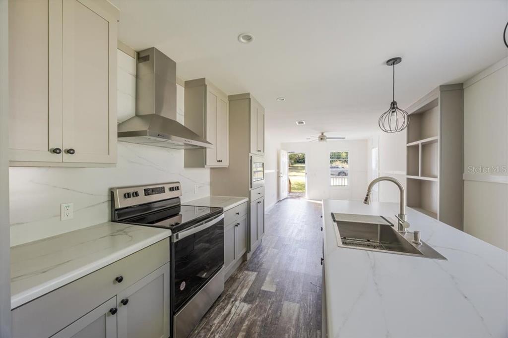 326 Smith Road Polk City, FL 33868 - Photo 16 of 26 a kitchen with granite countertop a stove a sink a refrigerator and wooden floor