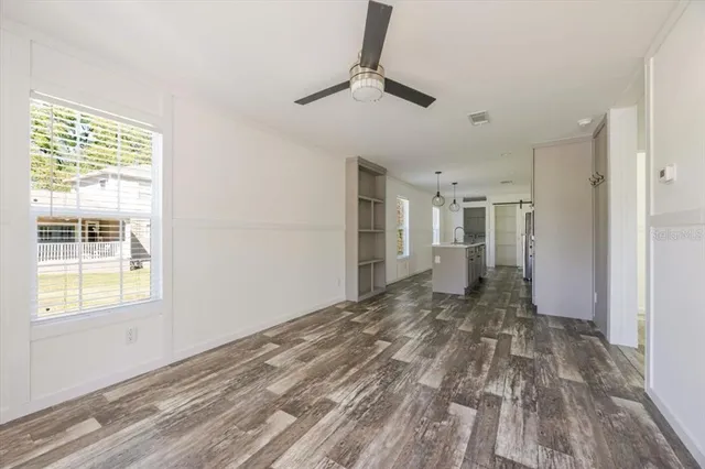 a view of empty room with wooden floor and fan