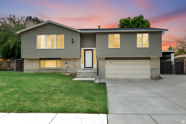 Split-level residence featuring gray horizontal siding and a brick-finish foundation