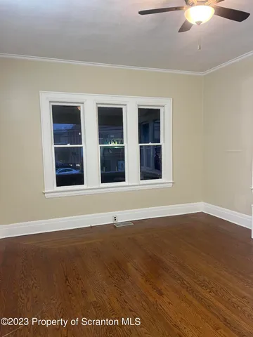 a view of an empty room with wooden floor and windows