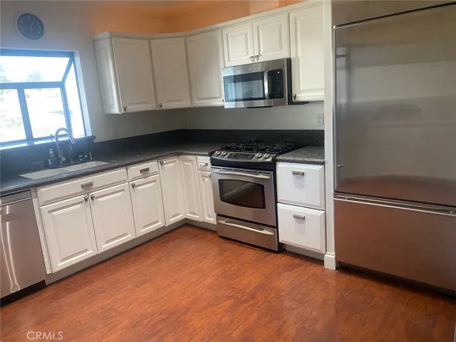 a kitchen with granite countertop white cabinets stainless steel appliances and sink
