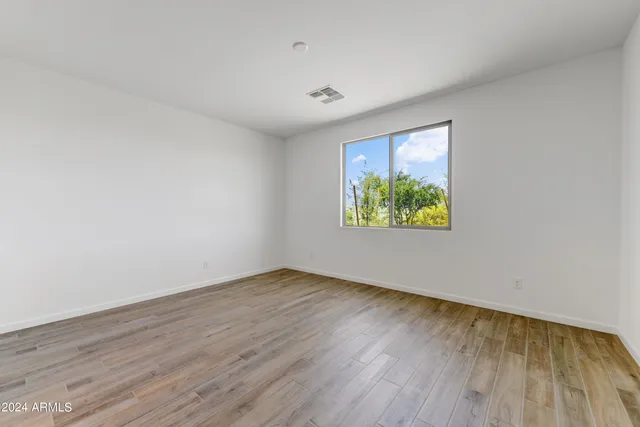 an empty room with wooden floor and window