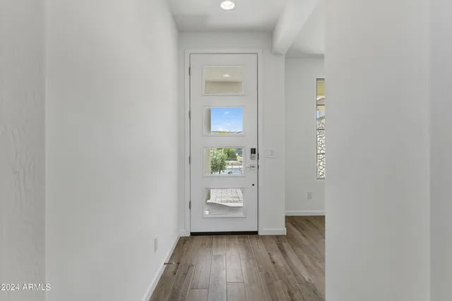 a view of a hallway to an empty room and wooden floor