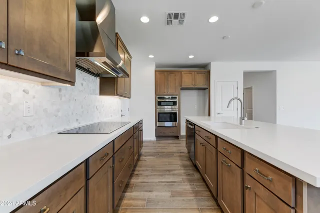 a large kitchen with stainless steel appliances a sink and cabinets