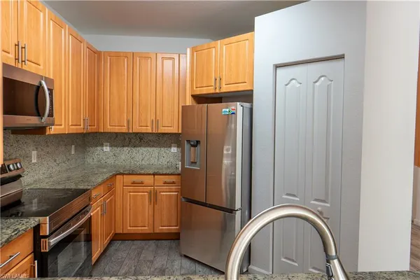a kitchen with stainless steel appliances granite countertop a refrigerator a stove a sink and a microwave