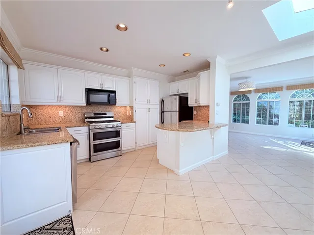 a large kitchen with a stove a sink dishwasher and a microwave oven on the kitchen countertops