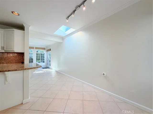 a view of an empty room with kitchen and window
