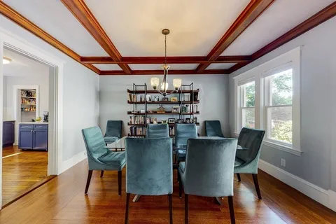 a dining room with furniture a chandelier and wooden floor