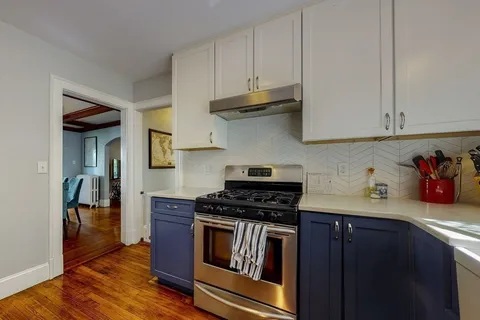 a kitchen with granite countertop a stove and a white cabinets