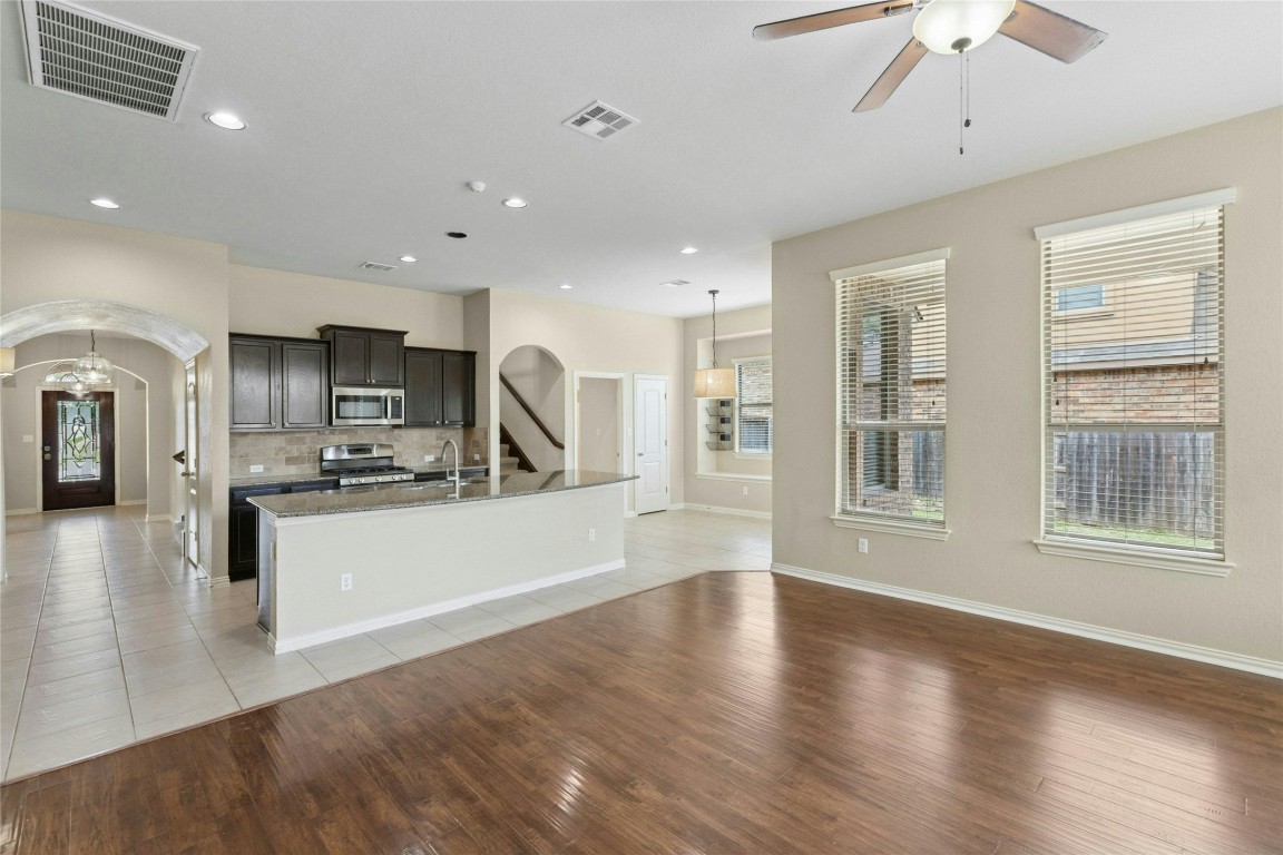 2804 Prosperity Leander, TX 78641 - Photo 12 of 39 Kitchen featuring arched walkways, stainless steel appliances, a kitchen island with sink, light wood finished floors, and recessed lighting