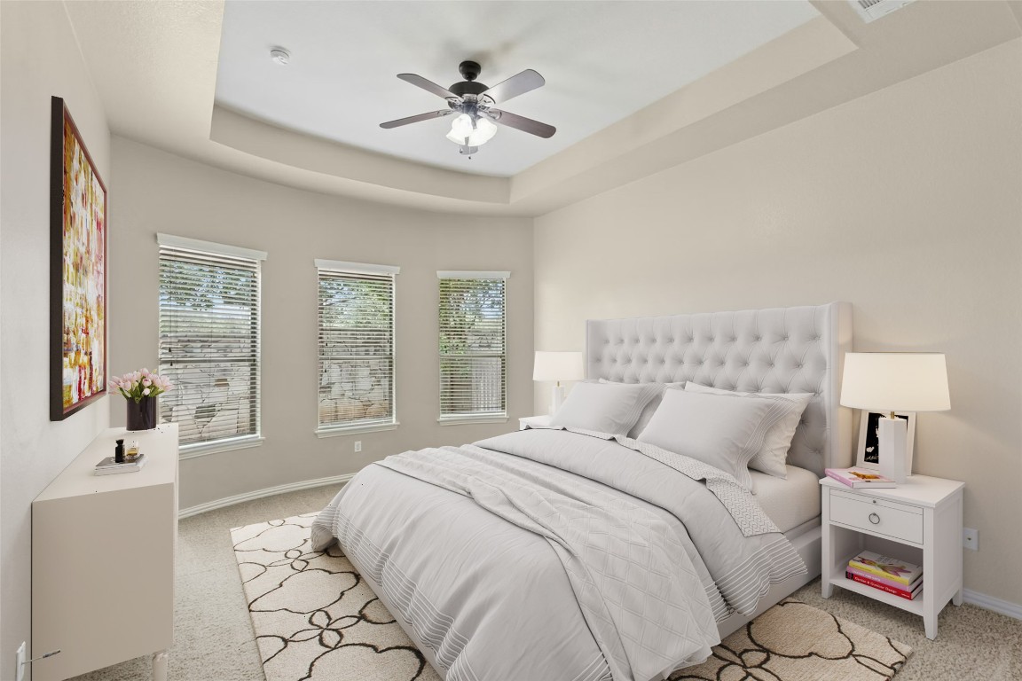 2804 Prosperity Leander, TX 78641 - Photo 15 of 39 Bedroom featuring a tray ceiling, carpet, multiple windows, and a ceiling fan
