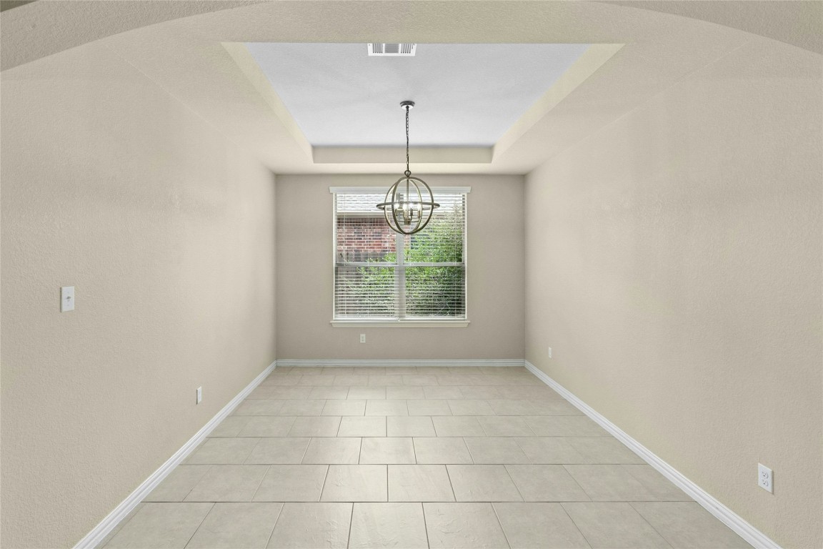 2804 Prosperity Leander, TX 78641 - Photo 6 of 39 Spare room with a chandelier, a tray ceiling, baseboards, and light tile patterned flooring