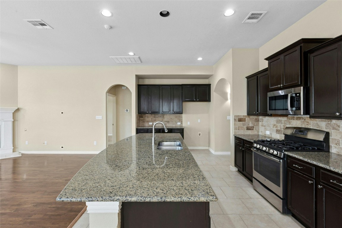 2804 Prosperity Leander, TX 78641 - Photo 9 of 39 Kitchen featuring appliances with stainless steel finishes, a sink, arched walkways, tasteful backsplash, and recessed lighting