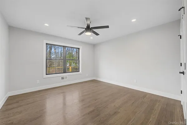 an empty room with wooden floor ceiling fan and windows