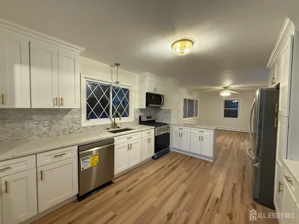 a large kitchen with a lot of counter space and wooden floor