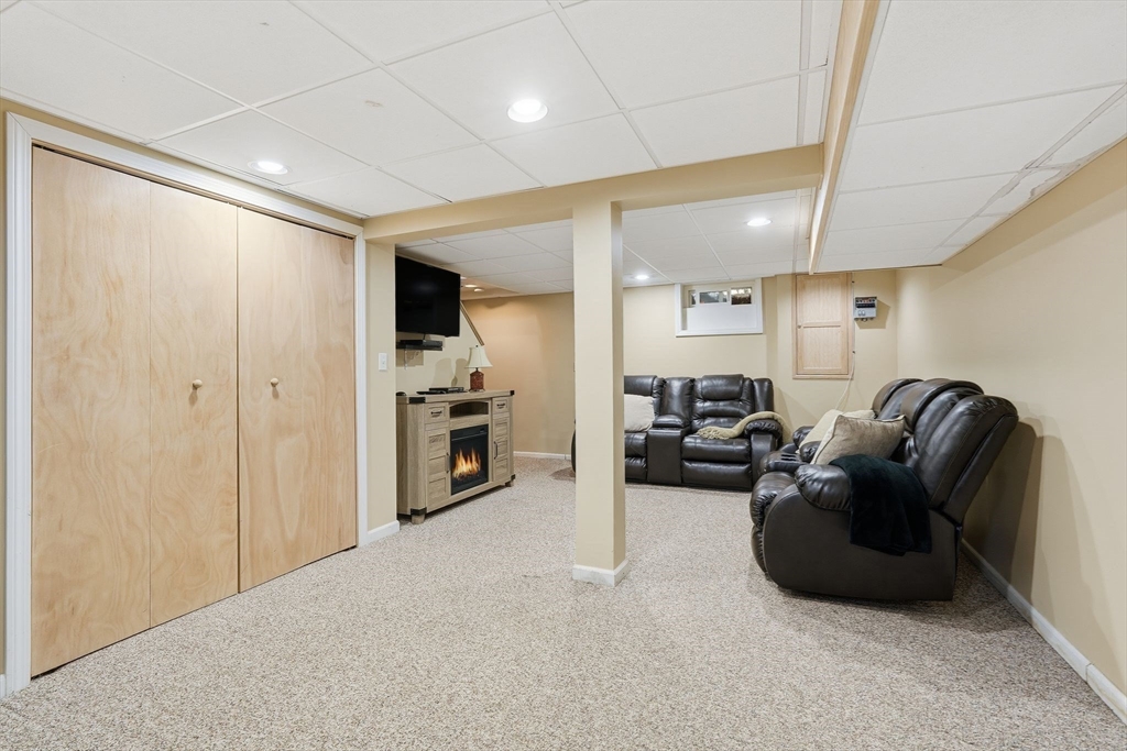 42 Redstone Drive Springfield, MA 01118 - Photo 30 of 37 a living room with furniture a refrigerator and a flat screen tv