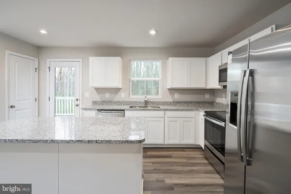 a kitchen with stainless steel appliances granite countertop a refrigerator sink and stove