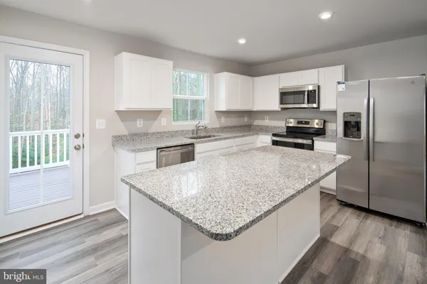 a kitchen with stainless steel appliances granite countertop a sink dishwasher a stove and a refrigerator
