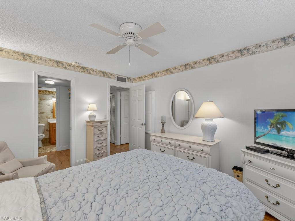 766 Central Avenue, Unit 101 Naples, FL 34102 - Photo 11 of 19 a bedroom with a bed and a chandelier