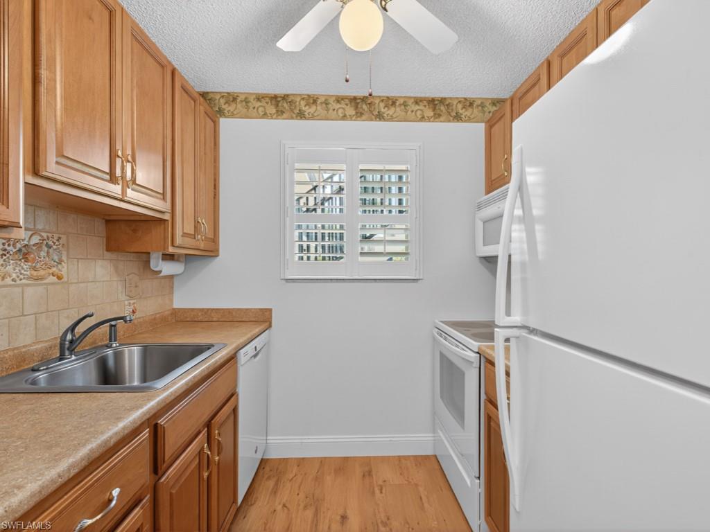 766 Central Avenue, Unit 101 Naples, FL 34102 - Photo 7 of 19 a kitchen with a sink a refrigerator and cabinets