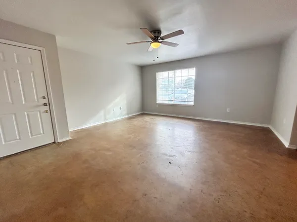 an empty room with windows and fan