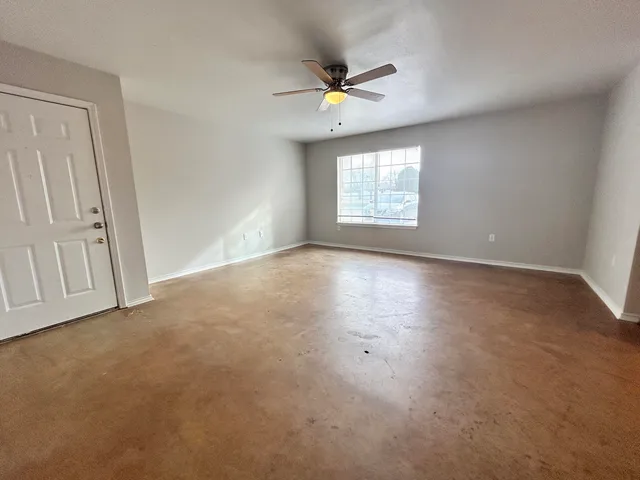 an empty room with windows and fan