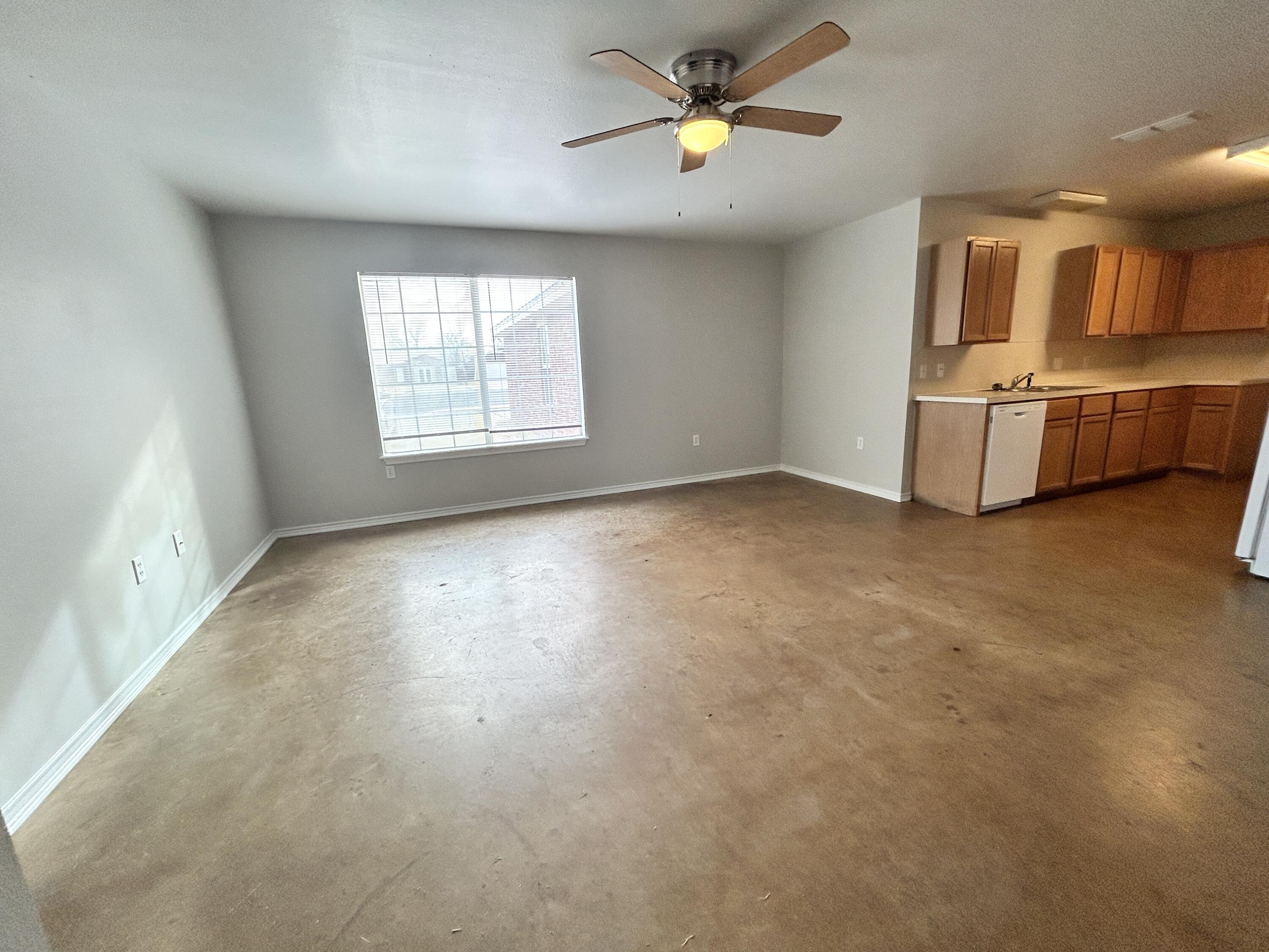 1106 82nd Street, Unit B Lubbock, TX 79423 - Photo 3 of 8 a view of an empty room with a window and kitchen view