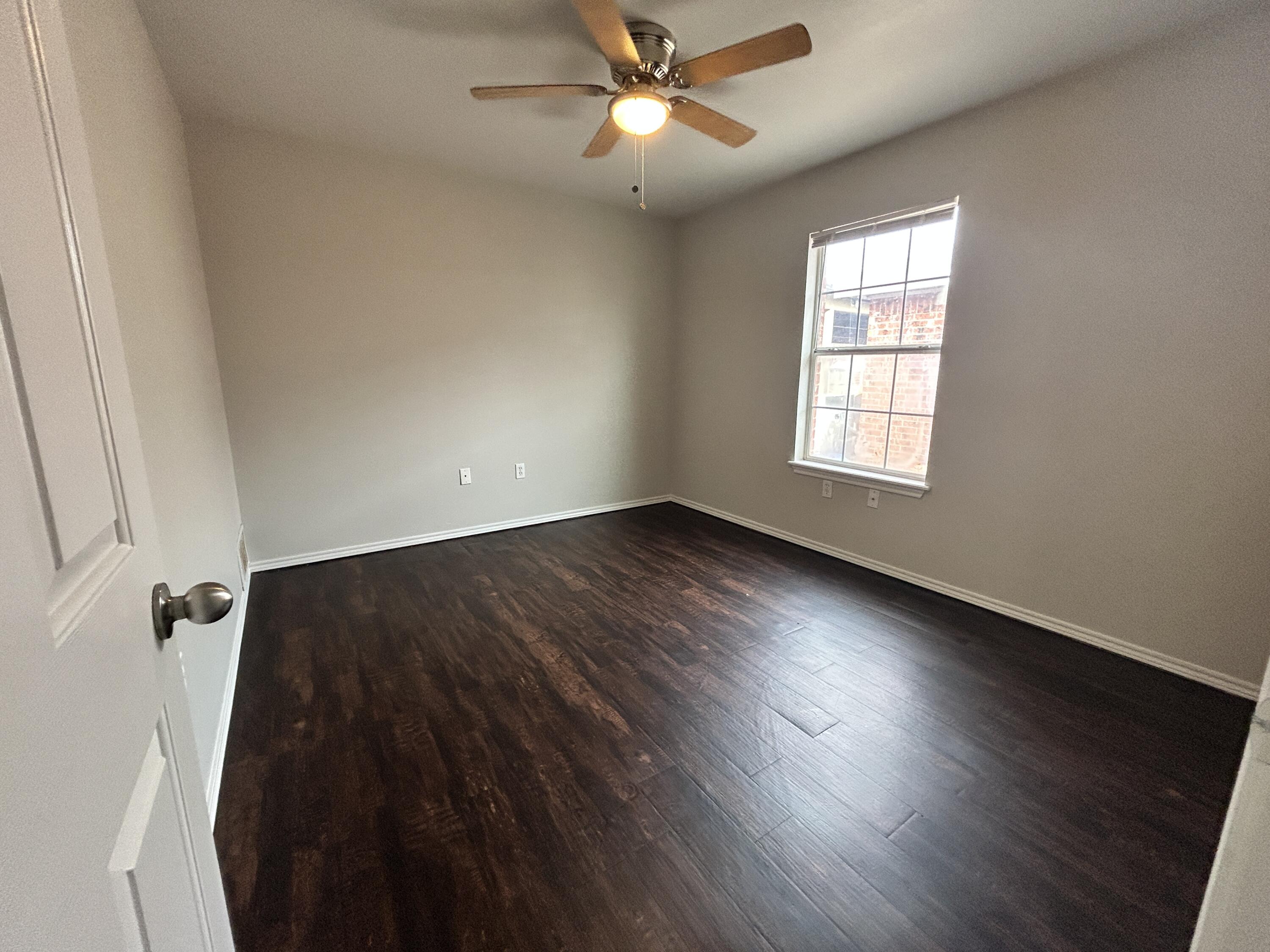 1106 82nd Street, Unit B Lubbock, TX 79423 - Photo 4 of 8 wooden floor in an empty room with a window