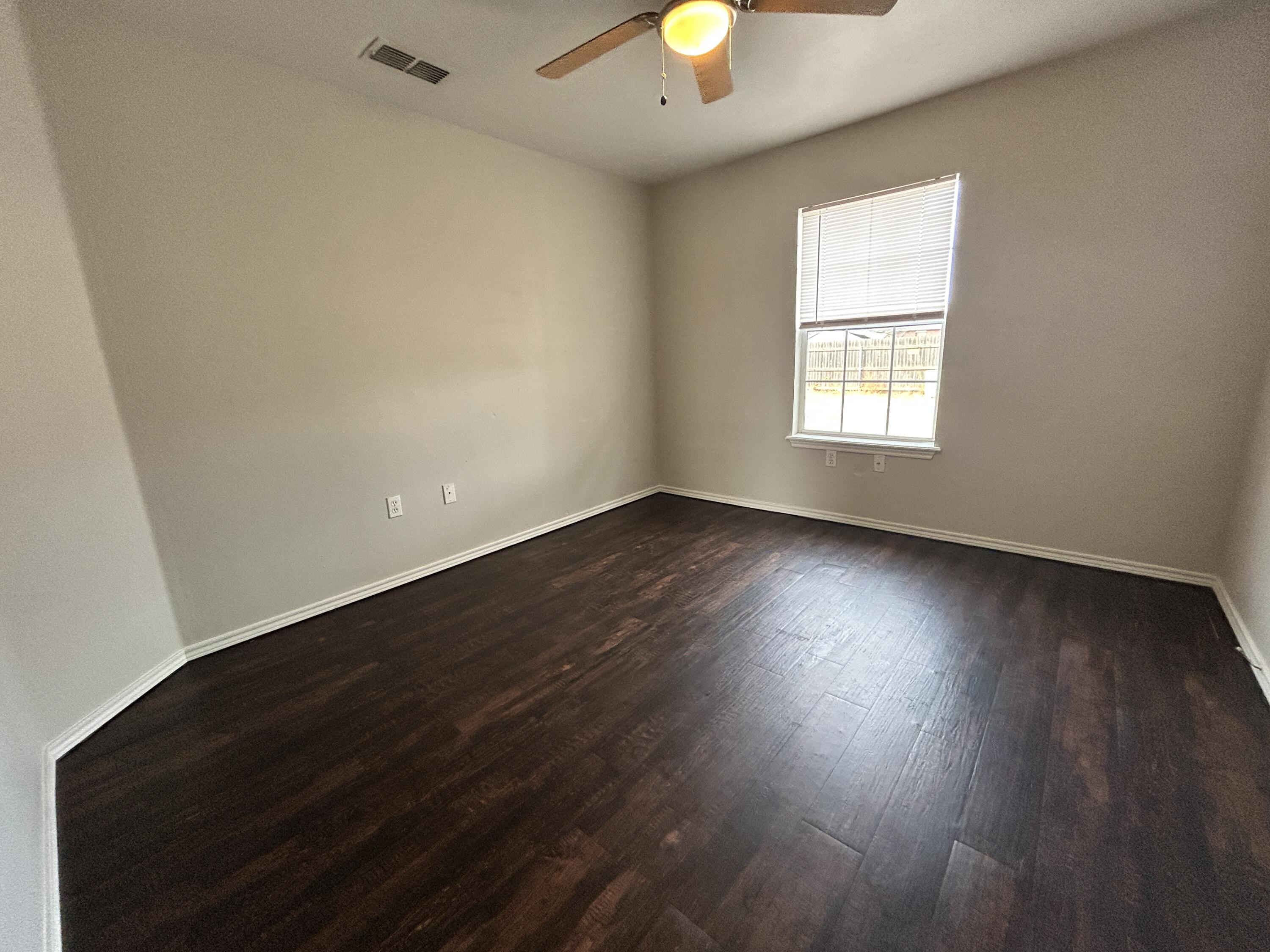 1106 82nd Street, Unit B Lubbock, TX 79423 - Photo 5 of 8 an empty room with wooden floor and windows