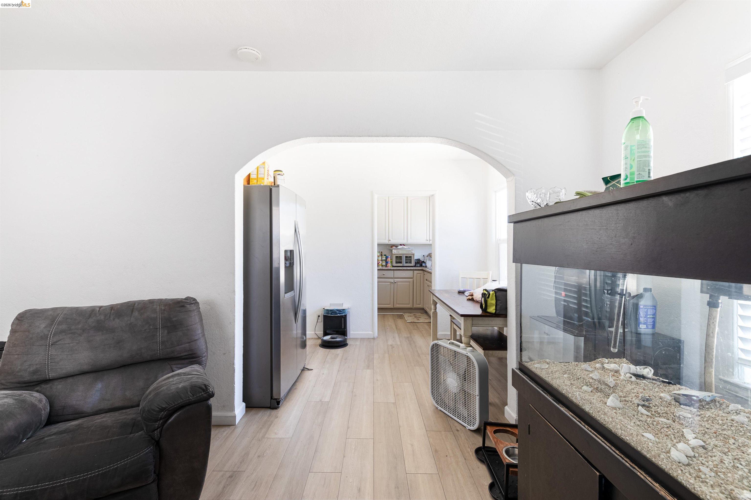 1821 74th Avenue Oakland, CA 94621 - Photo 27 of 27 Kitchen featuring light wood finished floors, stainless steel fridge with ice dispenser, arched walkways, light stone countertops, and open floor plan