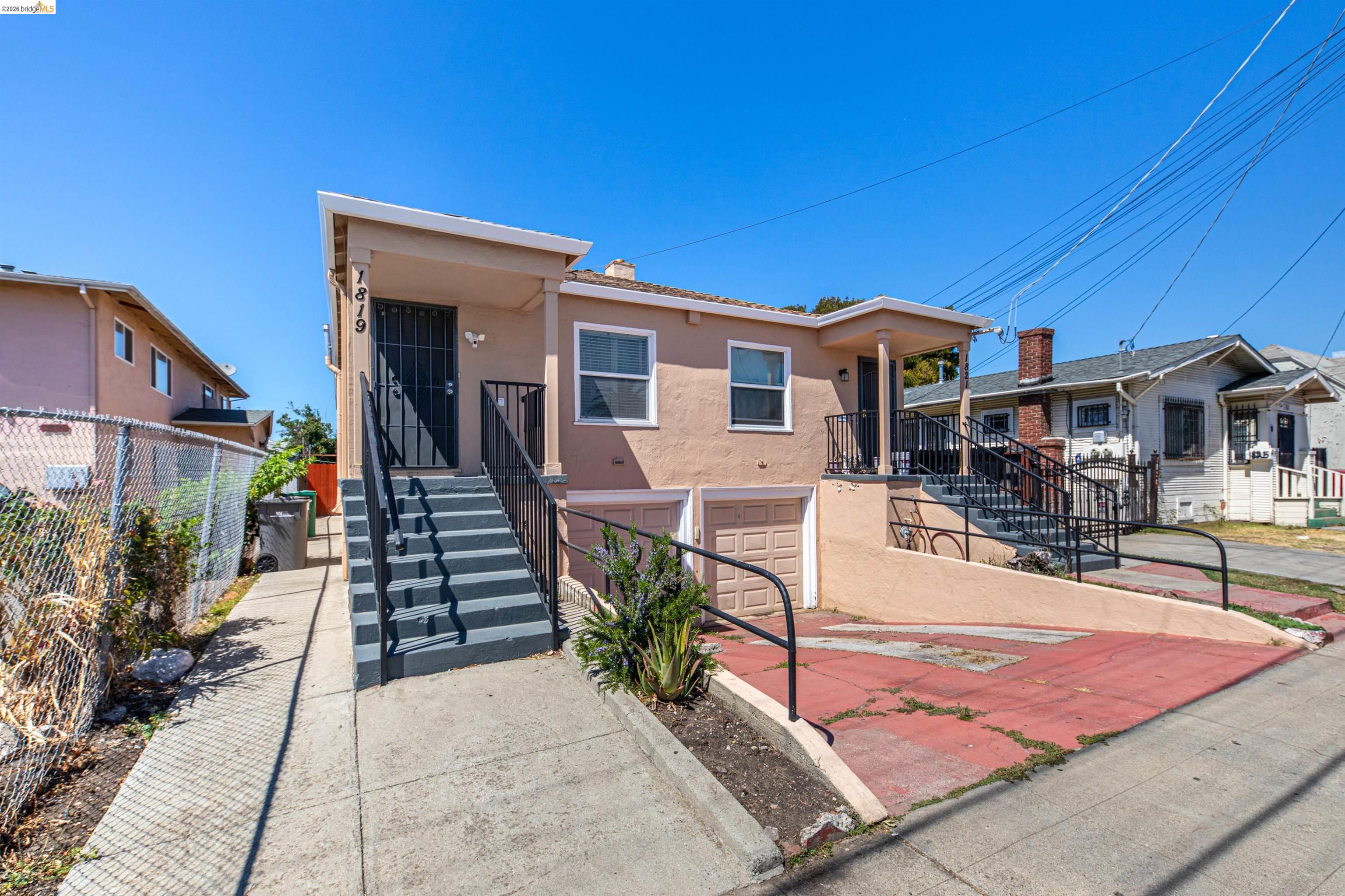 1821 74th Avenue Oakland, CA 94621 - Photo 2 of 27 View of front of home with stucco siding, an attached garage, stairway, and concrete driveway