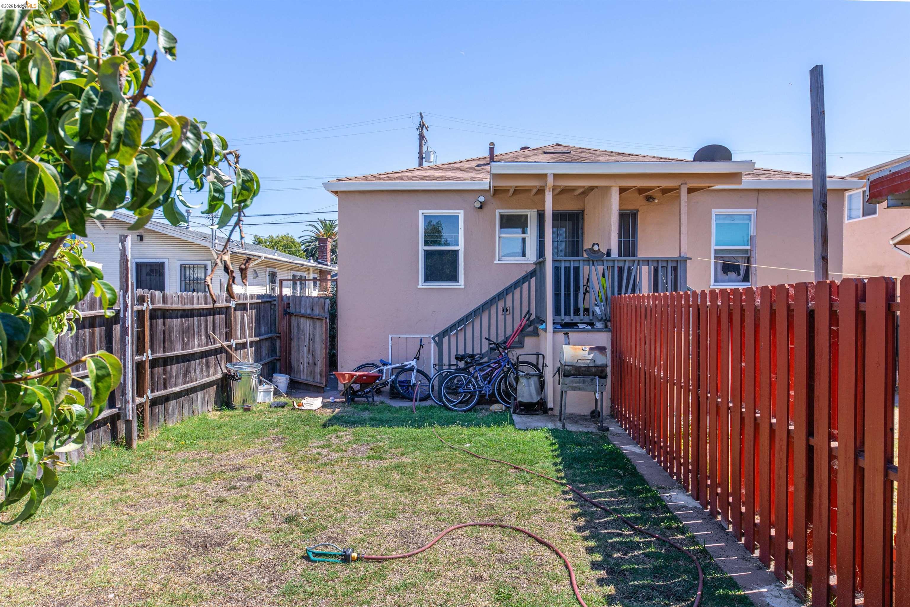 1821 74th Avenue Oakland, CA 94621 - Photo 26 of 27 Back of property featuring stucco siding, a fenced backyard, and a shingled roof