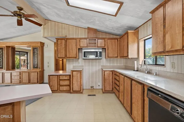 a kitchen with stainless steel appliances granite countertop a sink a stove a microwave cabinets and a window