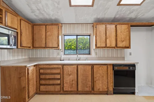 a kitchen with granite countertop a sink a stove cabinets and wooden floor
