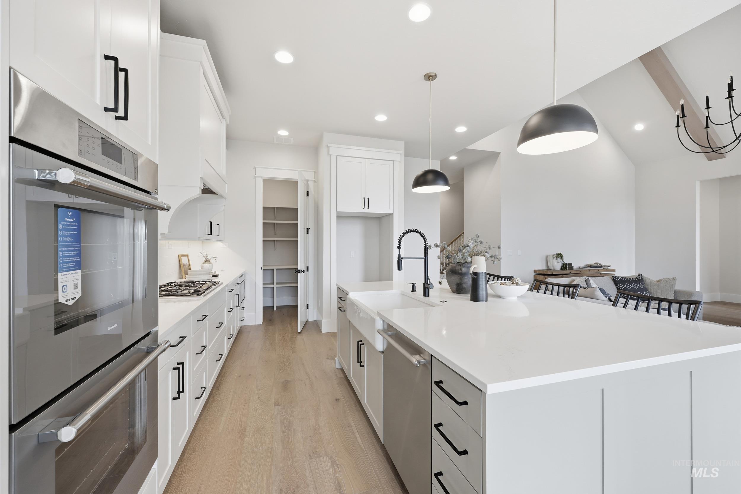6513 South Utmost Way Meridian, ID 83642 - Photo 11 of 47 Kitchen featuring stainless steel appliances, decorative light fixtures, a kitchen island with sink, light wood-type flooring, and recessed lighting