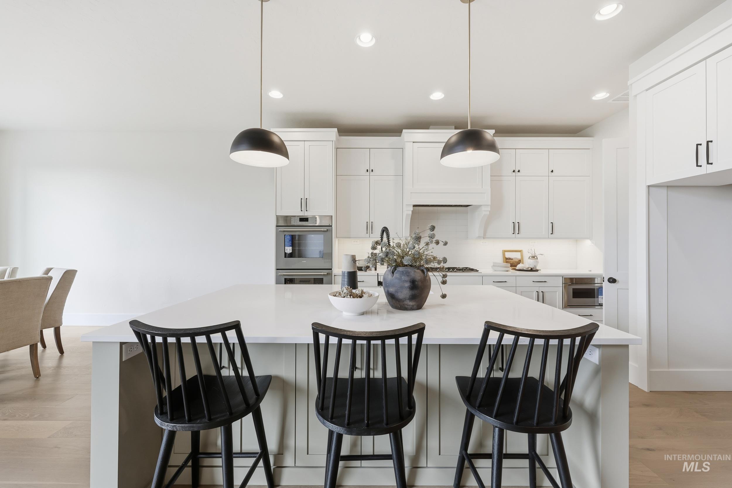 6513 South Utmost Way Meridian, ID 83642 - Photo 12 of 47 Kitchen featuring backsplash, white cabinets, a center island with sink, light wood-type flooring, and recessed lighting